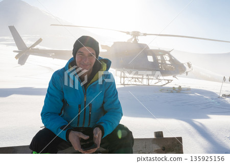 Offpiste heliskiing in fresh powder with a man and helicopter in the mountains 135925156