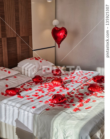 Medium View of Bed Decorated with Rose Petals and Heart Balloons 135925307