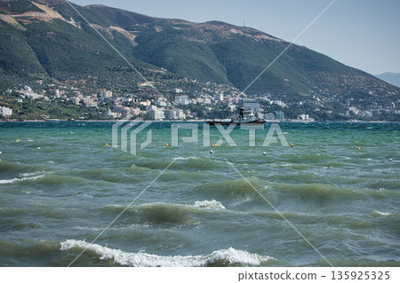 An evening view of the coastline of Vlora, Albania, taken in August 2025. Soft sunlight illuminates the rocky hills and seascape. 135925325