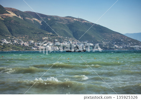 An evening view of the coastline of Vlora, Albania, taken in August 2025. Soft sunlight illuminates the rocky hills and seascape. 135925326