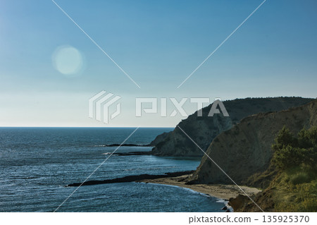 An evening view of the coastline of Vlora, Albania, taken in August 2025. Soft sunlight illuminates the rocky hills and seascape. 135925370