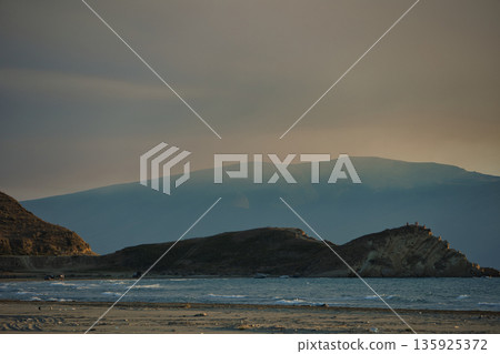 An evening view of the coastline of Vlora, Albania, taken in August 2025. Soft sunlight illuminates the rocky hills and seascape. 135925372