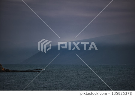 An evening view of the coastline of Vlora, Albania, taken in August 2025. Soft sunlight illuminates the rocky hills and seascape. 135925378