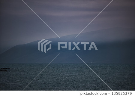 An evening view of the coastline of Vlora, Albania, taken in August 2025. Soft sunlight illuminates the rocky hills and seascape. 135925379