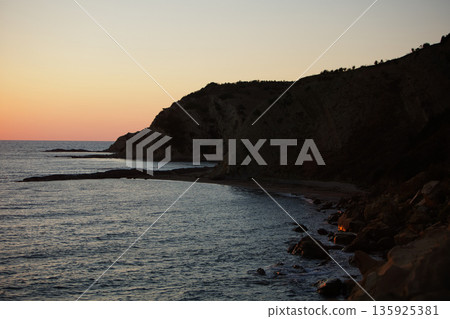 An evening view of the coastline of Vlora, Albania, taken in August 2025. Soft sunlight illuminates the rocky hills and seascape. An evening view of the coastline of Vlora, Albania, taken in August 2025. Soft sunlight illuminates the rocky hills and seascape. 135925381