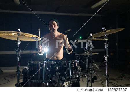 Male drummer performing rock music with energy on stage Male drummer performing rock music with energy on stage 135925837