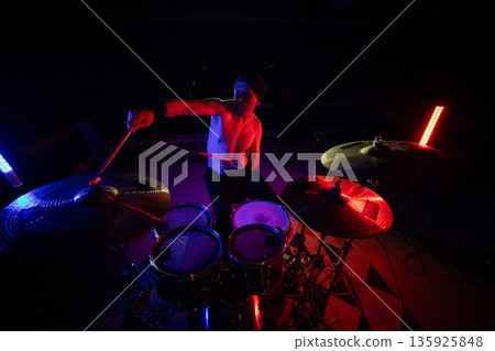 Drummer playing live music on stage with colorful lights Drummer playing live music on stage with colorful lights 135925848