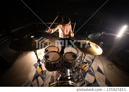 Bare chested drummer performing live music with drumsticks Bare chested drummer performing live music with drumsticks 135925851
