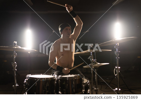 Drummer playing powerful drum solo on dark stage Drummer playing powerful drum solo on dark stage 135925869