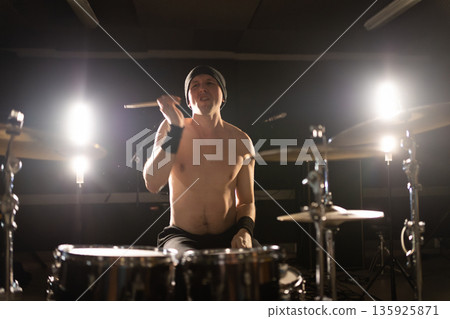 Shirtless drummer playing live performance drums in studio Shirtless drummer playing live performance drums in studio 135925871