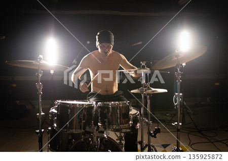 Drummer playing a drum set with backlights Drummer playing a drum set with backlights 135925872
