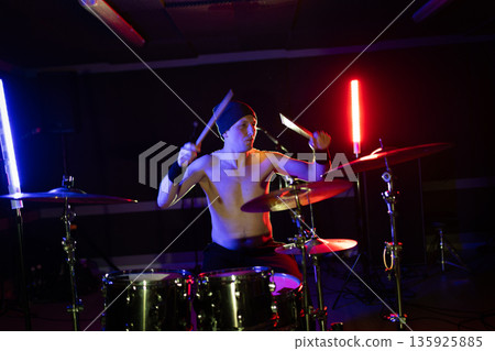 Drummer playing drums with colorful stage lights Drummer playing drums with colorful stage lights 135925885