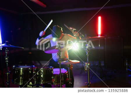 Drummer performing live on stage with drum kit 135925886