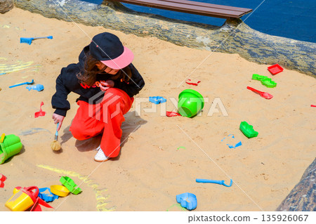 Good leisure for a child. Teaching a child through play. A handsome boy 3 oldl in a yellow jacket excavates the remains of dinosaurs. High quality photo. 135926067