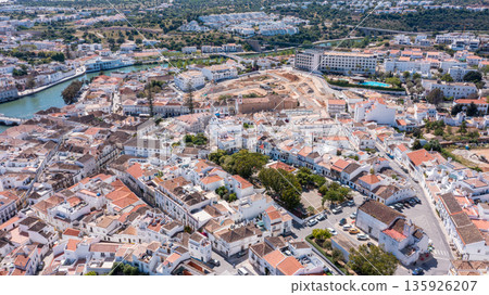 Tavira shows white houses and narrow streets from above, highlighting the town's layout, greenery, and surrounding hills on a clear day in Algarve, Portugal 135926207