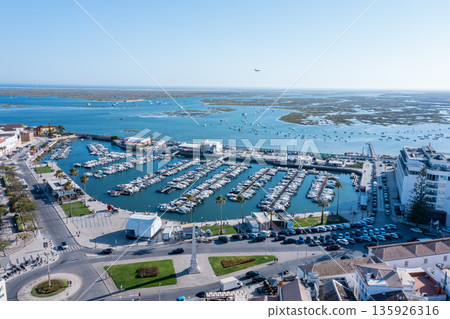 In Faro, Algarve, boats are docked at Ria Formosa. The view shows the busy marina and the surrounding waters with activity on a sunny day In Faro, Algarve, boats are docked at Ria Formosa. The view shows the busy marina and the surrounding waters with activity on a sunny day 135926316