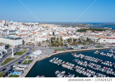 Tourists visit Ria Formosa and the old town in Faro while boats are docked. The scene shows the vibrant activity of the Algarve region in Portugal 135926325