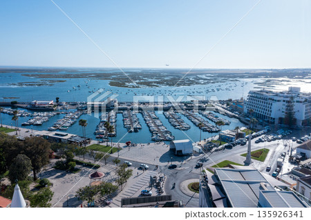 Tourists explore the Ria Formosa area in Faro, Algarve with its docks filled with boats and scenic views of the water and greenery Tourists explore the Ria Formosa area in Faro, Algarve with its docks filled with boats and scenic views of the water and greenery 135926341