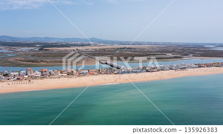 Aerial view captures Praia de Faro with its sandy beach, shoreline, and bridge over Ria Formosa on a sunny day in Portugal Aerial view captures Praia de Faro with its sandy beach, shoreline, and bridge over Ria Formosa on a sunny day in Portugal 135926383