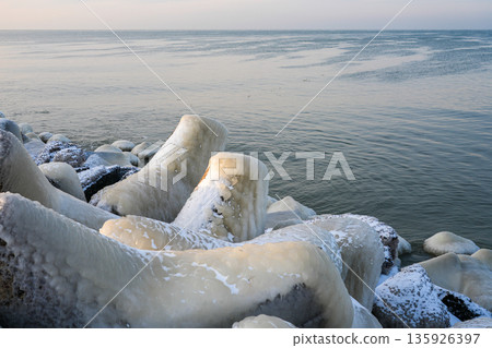 Ice-covered breakwater rocks on the Baltic Sea coast in Liepaja during a calm winter morning Ice-covered breakwater rocks on the Baltic Sea coast in Liepaja during a calm winter morning 135926397