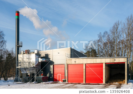 Modern wood chip boiler house with biomass heating system and red storage doors in winter 135926408