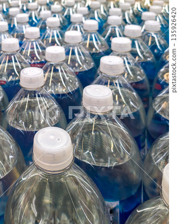 Close-up of bottled water with white caps arranged in rows on a supermarket shelf Close-up of bottled water with white caps arranged in rows on a supermarket shelf 135926420