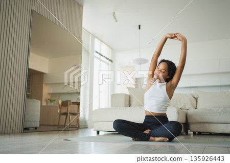Yoga fitness workout training. Healthy African girl practicing yoga at home. Woman training Pilates doing sports exercise on yoga mat indoor. Girl have training workout for weight loss. Sport fitness Yoga fitness workout training. Healthy African girl practicing yoga at home. Woman training Pilates doing sports exercise on yoga mat indoor. Girl have training workout for weight loss. Sport fitness 135926443