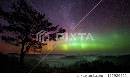 Scenic mountain landscape under a starry night sky with bright aurora borealis Scenic mountain landscape under a starry night sky with bright aurora borealis 135926531