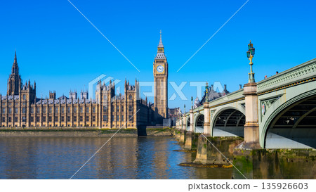 The Houses of Parliament and Big Ben above the River Thames in London. The sky is clear and the iconic landmarks stand tall and proud. The Houses of Parliament and Big Ben above the River Thames in London. The sky is clear and the iconic landmarks stand tall and proud. 135926603