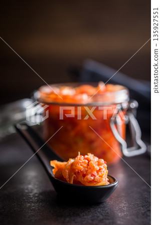 Fermented cabbage. Kimchi. Korean food in ceramic spoon on black table. Fermented cabbage. Kimchi. Korean food in ceramic spoon on black table. 135927551