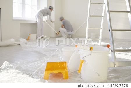 Painters renovate bright interior, wall painting with roller, ladder and bucket 135927778