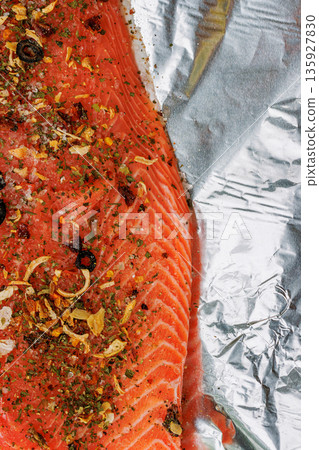 Vertical close up of a raw salmon fillet seasoned with herbs, spices, and garlic on crinkled aluminum foil, with copy space Vertical close up of a raw salmon fillet seasoned with herbs, spices, and garlic on crinkled aluminum foil, with copy space 135927830