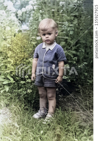A vintage portrait of a little boy on a sunny day in the garden. The expression on the child's face is evident. Retro photo from 1969. 135927915