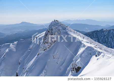 Mt. Tanigawa in the dead of winter. Toma-no-mimi seen from Oki-no-mimi and the silhouette of climbers. Mt. Tanigawa in the dead of winter. Toma-no-mimi seen from Oki-no-mimi and the silhouette of climbers. 135928127