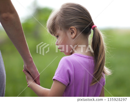 Little girl holding a hand of her mother. Family relations concept. Little girl holding a hand of her mother. Family relations concept. 135928297
