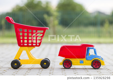 Bright plastic colorful toys for children outdoors on sunny summer day. Car truck and shopping pushcart. Bright plastic colorful toys for children outdoors on sunny summer day. Car truck and shopping pushcart. 135928298