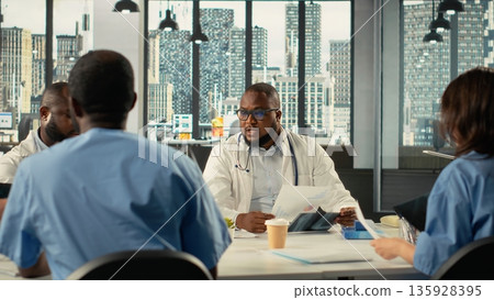 Doctors and nurses participating in a healthcare team meeting to review patient care strategies. The discussion focuses on treatment planning and advancement in modern medicine. 135928395