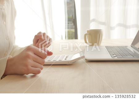 一位女士正在用計算機計算錢。 135928532