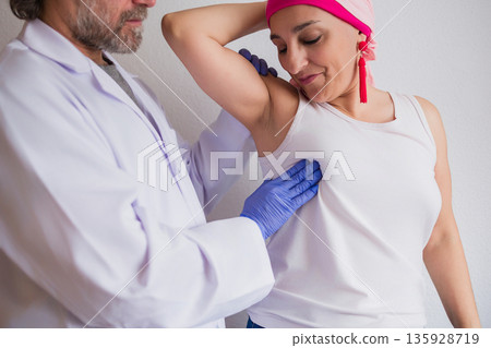 Doctor performing breast examination on woman patient with headscarf 135928719