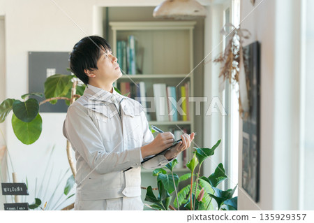 A man in work clothes inspecting indoor equipment 135929357