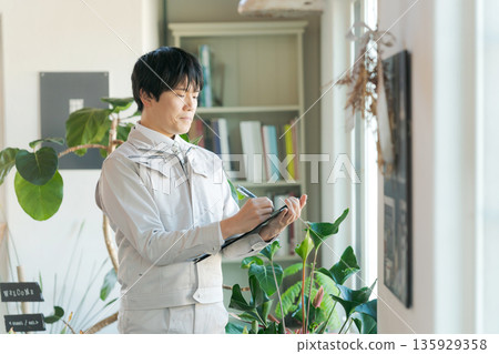 A man in work clothes inspecting indoor equipment 135929358