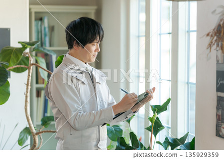 A man in work clothes inspecting indoor equipment 135929359