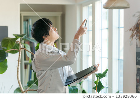 A man in work clothes inspecting indoor equipment 135929360
