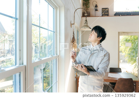 A man in work clothes inspecting indoor equipment 135929362