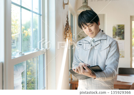 A man in work clothes inspecting indoor equipment 135929366