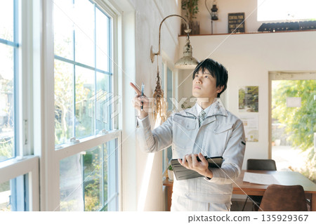 A man in work clothes inspecting indoor equipment 135929367