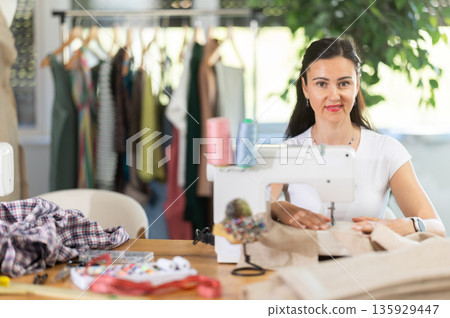 Woman tailor sews clothes in sewing machine Woman tailor sews clothes in sewing machine 135929447