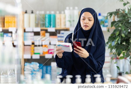 Muslim woman scans qr packages with pills Muslim woman scans qr packages with pills 135929472