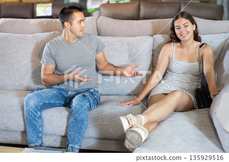 In store,husband and wife are sitting on gray sofa and choose upholstered furniture for living room In store,husband and wife are sitting on gray sofa and choose upholstered furniture for living room 135929516