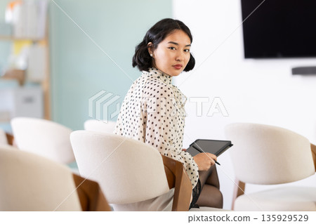 Young woman student taking notes on tablet in lecture hall Young woman student taking notes on tablet in lecture hall 135929529